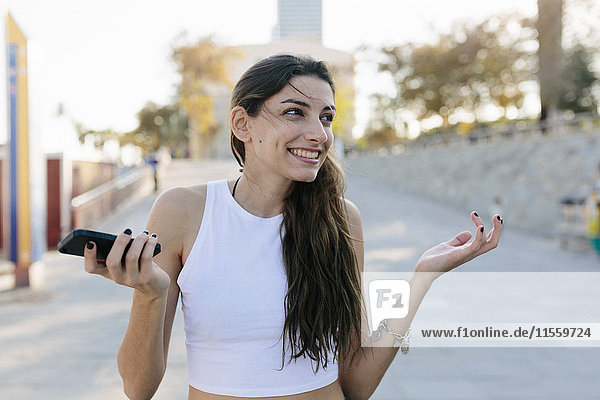 Portrait of grinning young woman with cell phone