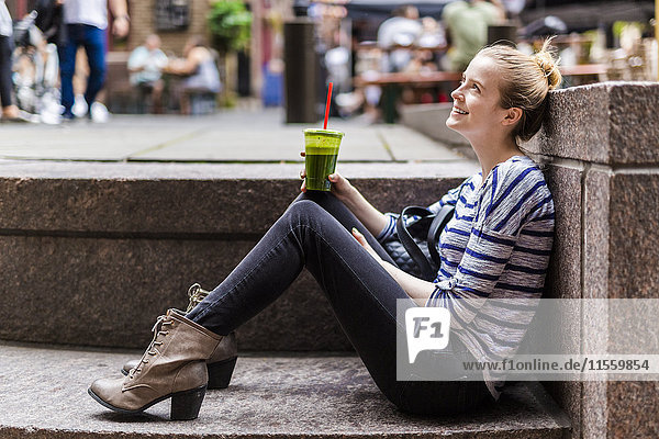 USA  New York City  smiling woman having a break drinking a smoothie in Manhattan