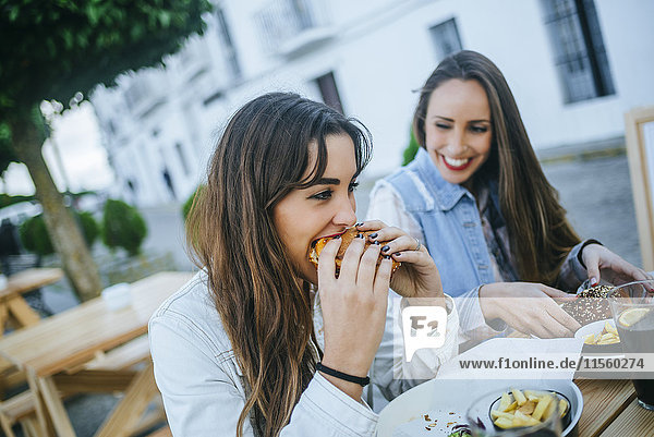 Zwei Frauen essen Hamburger in einem Straßenrestaurant