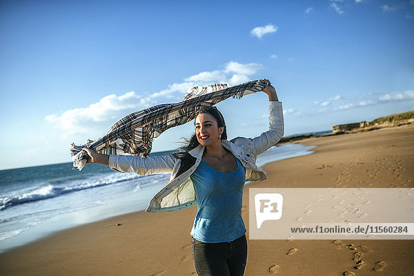 Junge Frau mit Decke im Wind am Strand