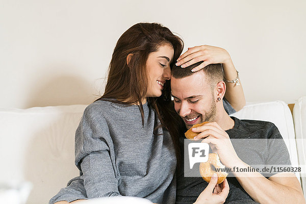 Amorous couple sitting on couch  having breakfast