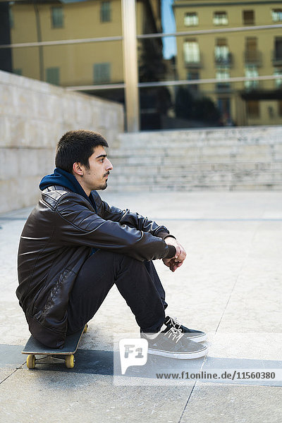 Young man sitting on skateboard