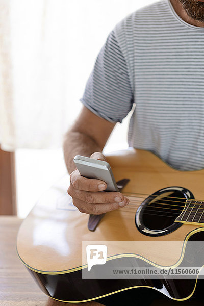 Close-up of man with guitar and cell phone
