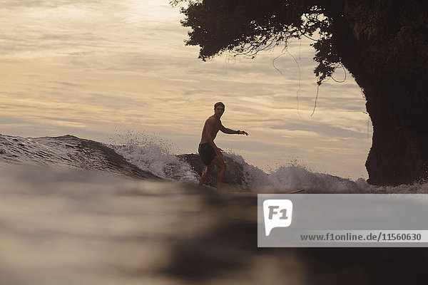 Indonesien  Java  Mann beim Surfen bei Sonnenuntergang