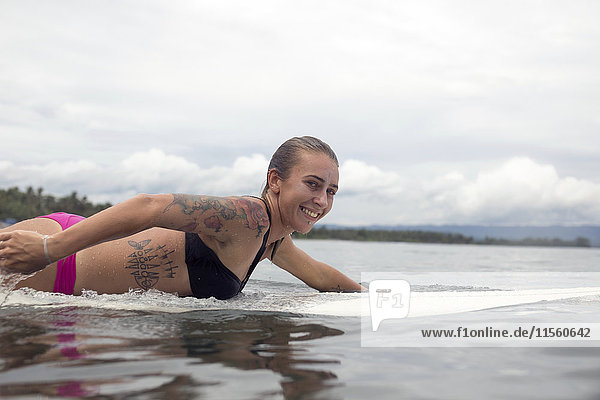 Indonesien  Java  lächelnde Frau auf dem Surfbrett auf dem Meer liegend