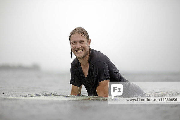 Indonesia  Java  smiling man on surfboard on the sea