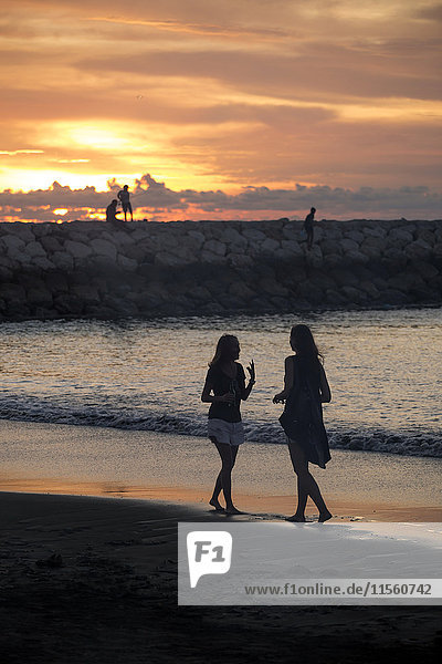 Indonesia  Bali  two women walking on the beach at sunset
