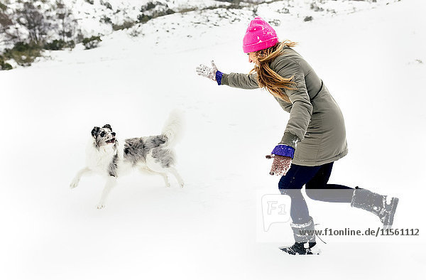 Young woman playing with her dog in the snow