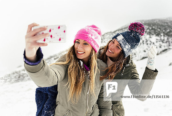 Zwei Freunde  die sich mit dem Smartphone im Schnee austoben