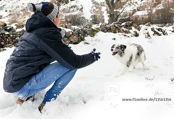 Young man playing with his dog in the snow
