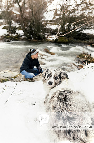 Junger Mann im Schnee mit seinem Hund