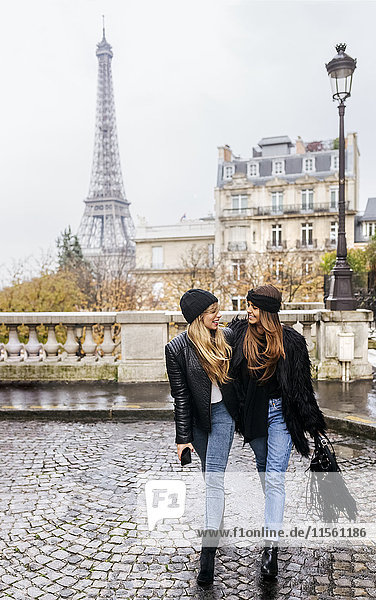France  Paris  two best friends walking down the street with the Eiffel Tower in the background