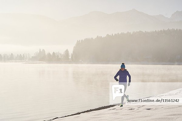 Germany  Bavaria  Lake Walchen  woman jogging in winter