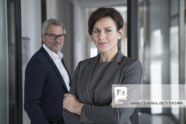 Portrait of confident businesswoman with businessman in background