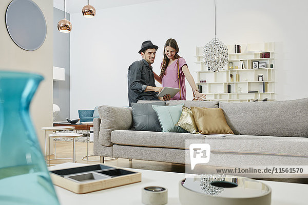 Couple choosing furniture in shop  using digital tablet