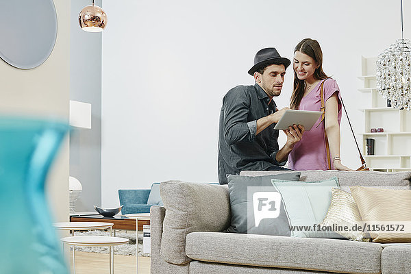 Couple choosing furniture in shop  using digital tablet