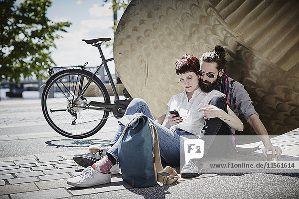 Deutschland  Hamburg  Pärchen auf Fahrradtour beim Blick aufs Handy