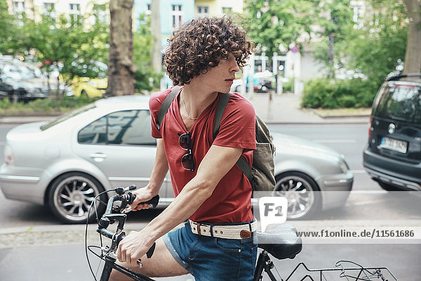 Junger Mann beim Radfahren auf dem Bürgersteig  der sich umdreht