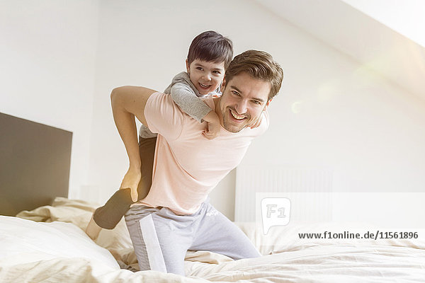 Glücklicher Vater und Sohn beim Spielen im Bett