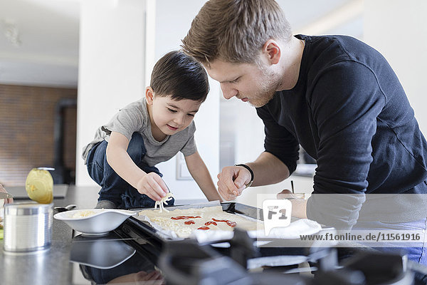 Father and son preparing pizza in kitchen together