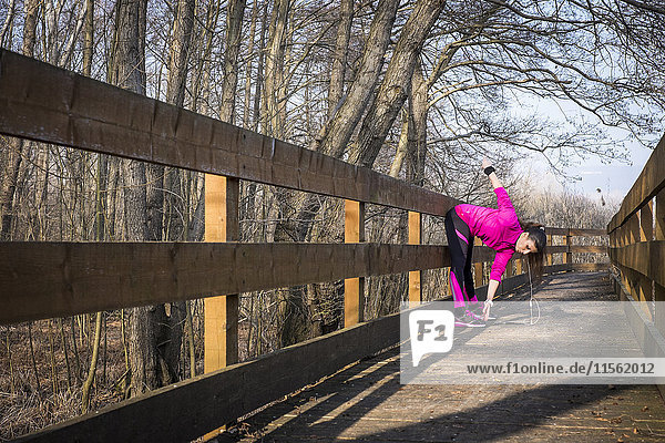 Woman stretching on wooden bridge in forest