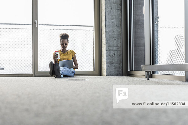 Young woman sitting on floor using laptop