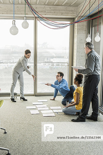 Businesspeople looking at documents on office floor