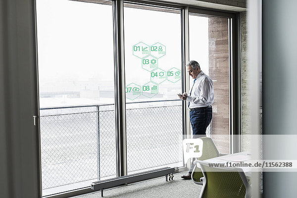 Businessman standing at windowpane with data in office