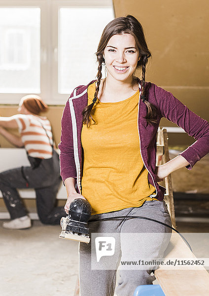 Young woman sanding planks on construction site of her new home