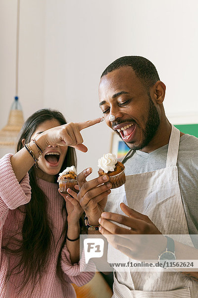 Young couple having fun  eating fresh cupcakes