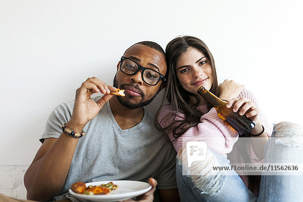 Junges Paar zu Hause beim Pizza essen und Bier trinken