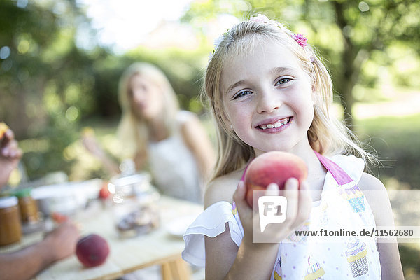 Porträt eines lächelnden Mädchens mit Pfirsich im Freien