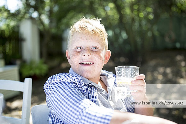 Porträt eines Jungen  der ein Glas Wasser im Freien trinkt.