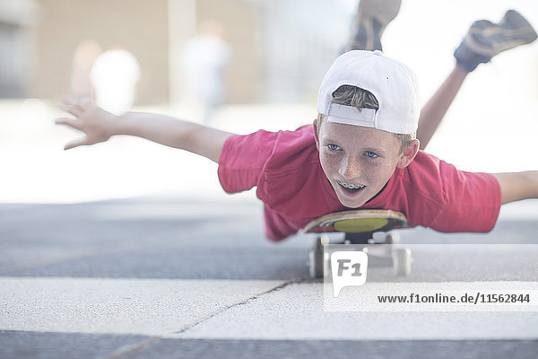 Boy Skateboarding auf der Straße  auf dem Bauch liegend