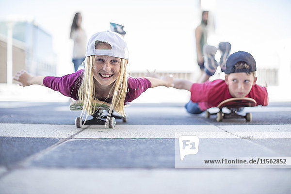 Kinderskateboarden auf der Straße  auf dem Bauch liegend