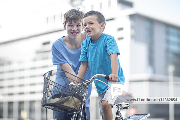 Junge  der dem kleinen Bruder beibringt  wie man ein Fahrrad fährt.