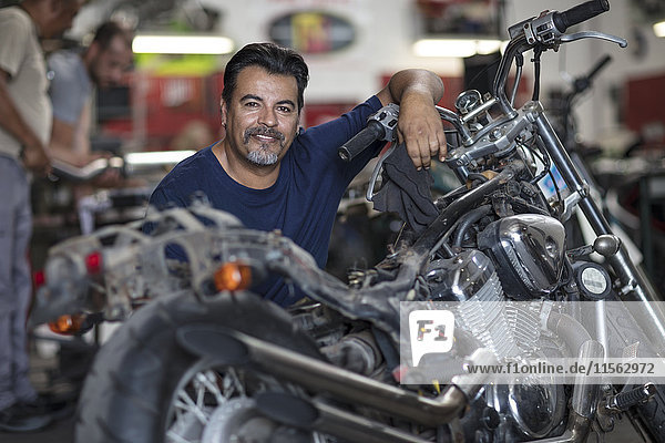 Porträt eines lächelnden Mechanikers in der Motorradwerkstatt