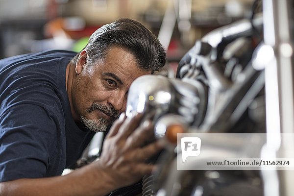 Mechanic examining motorcycle in workshop