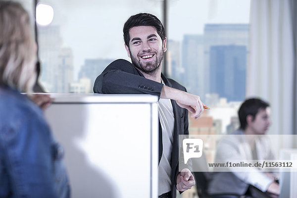 Man in office smiling at female colleague