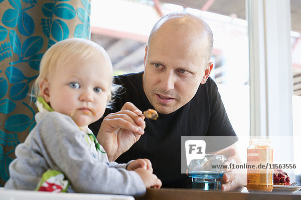 Schweden  Vater füttert Baby-Sohn (12-17 Monate)