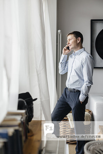 Deutschland Mann mit Handy am Fenster