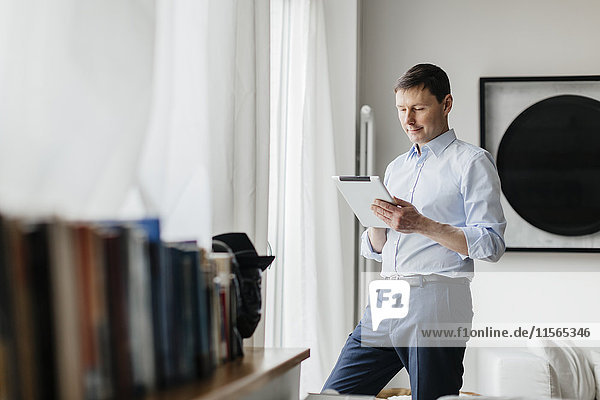 Deutschland Mann mit Tablette am Fenster