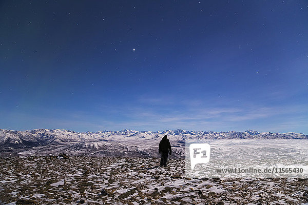 Ein Mann blickt in einer mondhellen Nacht vom Gipfel des Donnelly Dome auf die Alaska Range (das helle Objekt am Himmel ist Jupiter); Alaska  Vereinigte Staaten von Amerika'.