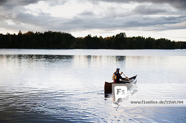 Sweden  Smaland  Man swimming in lake in boat