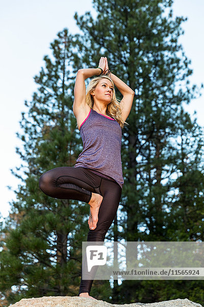 'Young woman doing yoga on top of a boulder; California  United States of America'