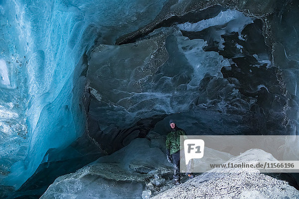 Ein Mann steht an einem kalten Wintertag auf einem großen Stück Eis in einer Höhle des Canwell-Gletschers in der Alaska Range; Alaska  Vereinigte Staaten von Amerika'.
