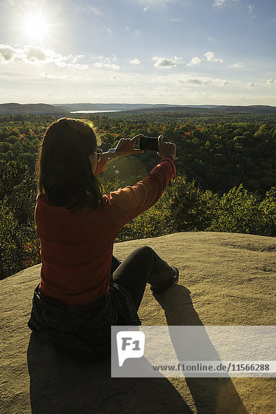 'Woman taking photos with a smart phone in Algonquin Park; Ontario  Canada'