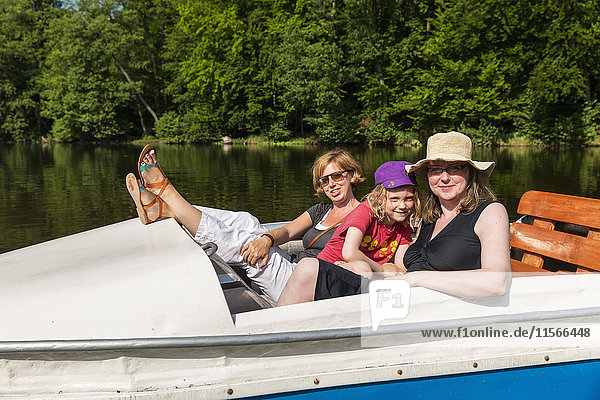 'Two women and a girl on a paddle boat on a calm river surrounded by dense forests on a sunny day; Steinbrucker Teig  Hessen  Germany'