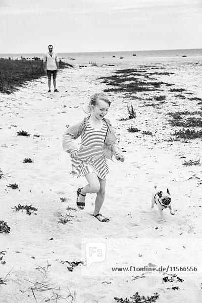 Mädchen läuft mit Hund am Meer