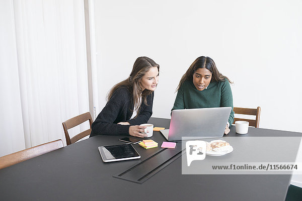 Two women using laptop in office